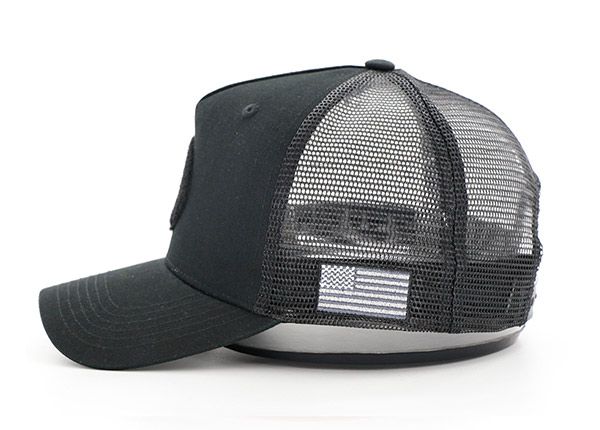 Side of All Black Trucker Hat With a Black Velcro Logo & a American Flag Logo on Side
